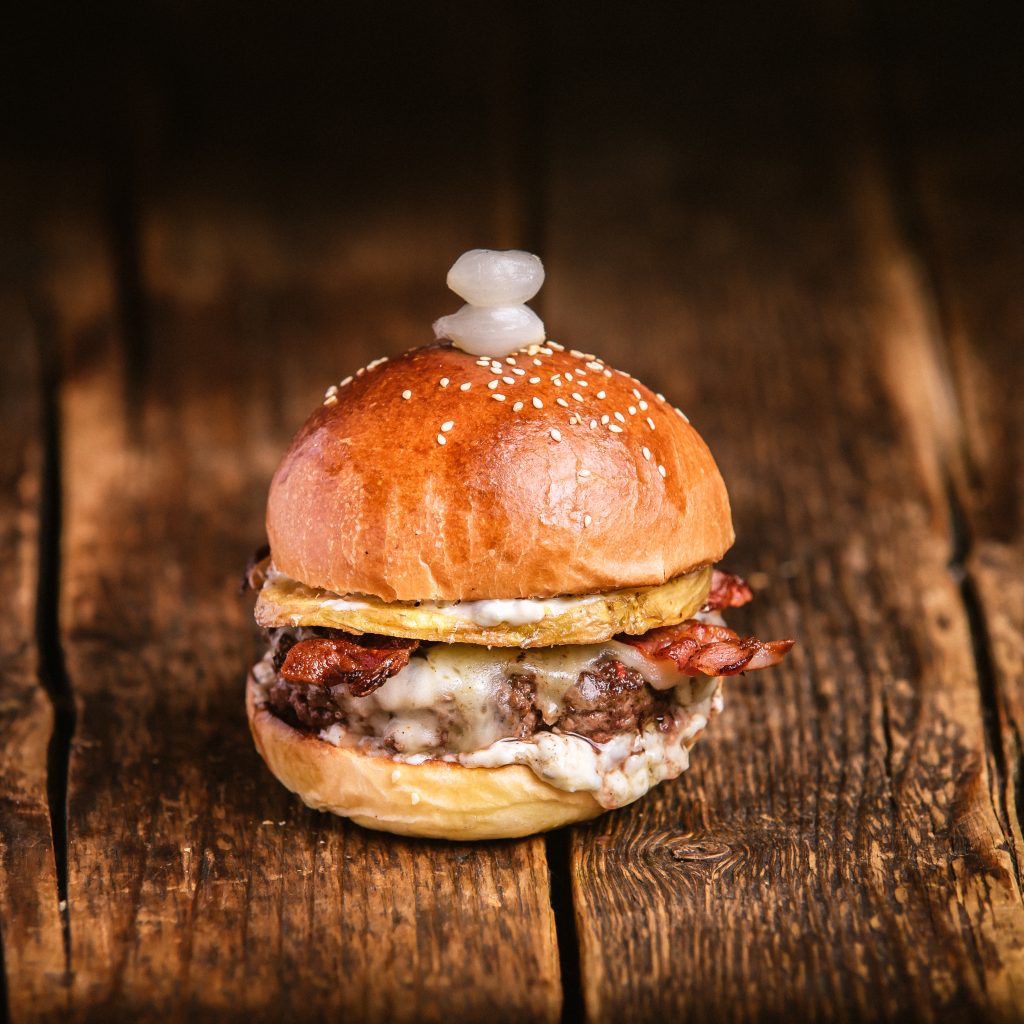 RACLETTE BURGER (#BAZILIKA)- MARHAHÚSPOGÁCSA, RACLETTE SAJT, CSEMEGEUBORKÁS AIOLI, GRILL BACON, SZÍNESBORSOS GRILL BURGONYA, SAVANYÍTOTT GYÖNGYHAGYMA - Bamba marha hamburger burger budapest